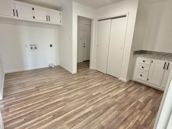 a view of a kitchen with white cabinets and wooden floor