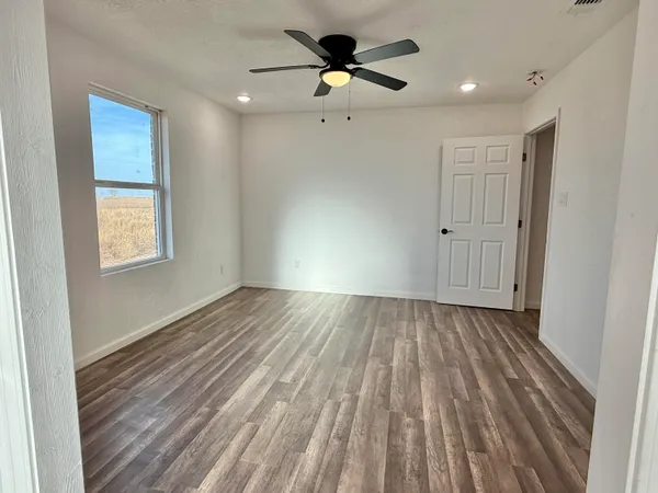 a view of empty room with wooden floor and fan
