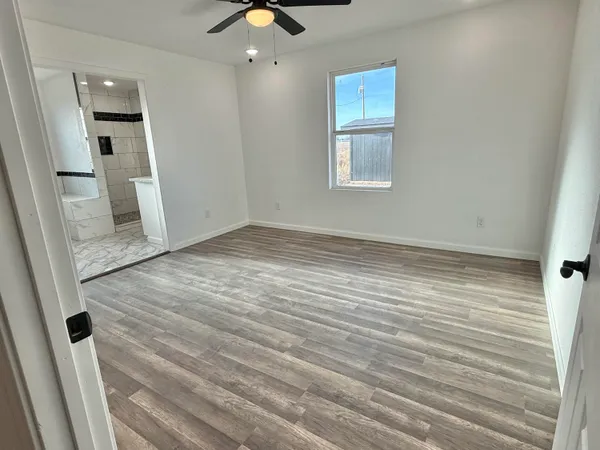 an empty room with wooden floor and windows