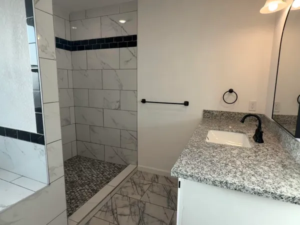 a bathroom with a granite countertop sink and a mirror