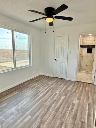 a view of empty room with wooden floor and fan