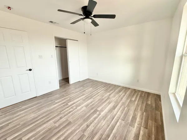 a view of empty room with wooden floor and fan