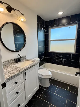 a bathroom with a granite countertop toilet sink and mirror