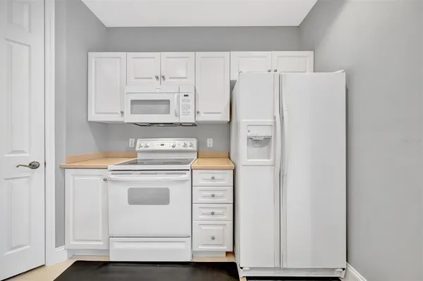 an empty room with a chandelier fan and windows