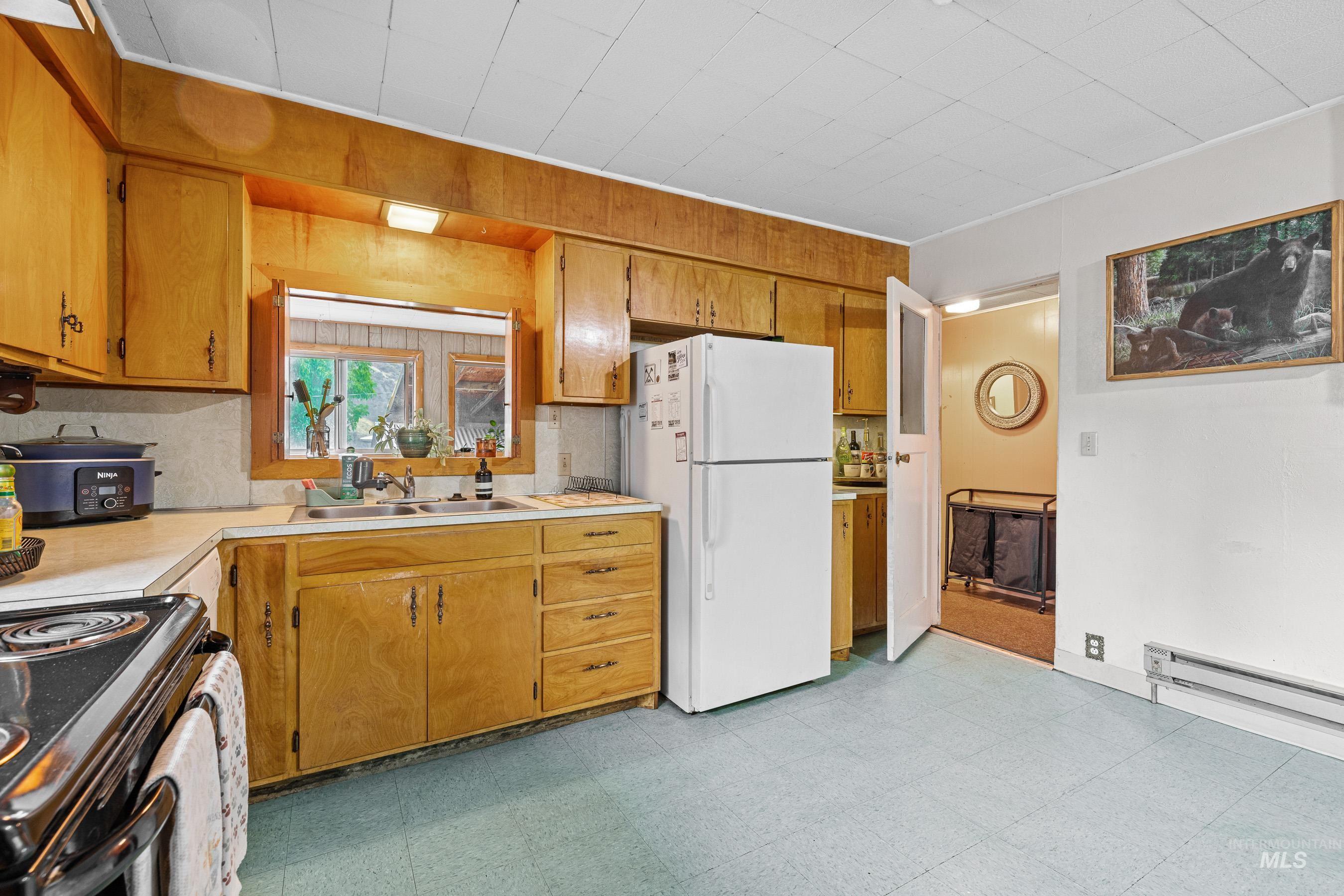 620 South Main Street Riggins, ID 83549 - Photo 4 of 23 Wood-finish cabinetry with coordinating wall paneling, light-toned countertops, double basin sink, and a built-in window opening