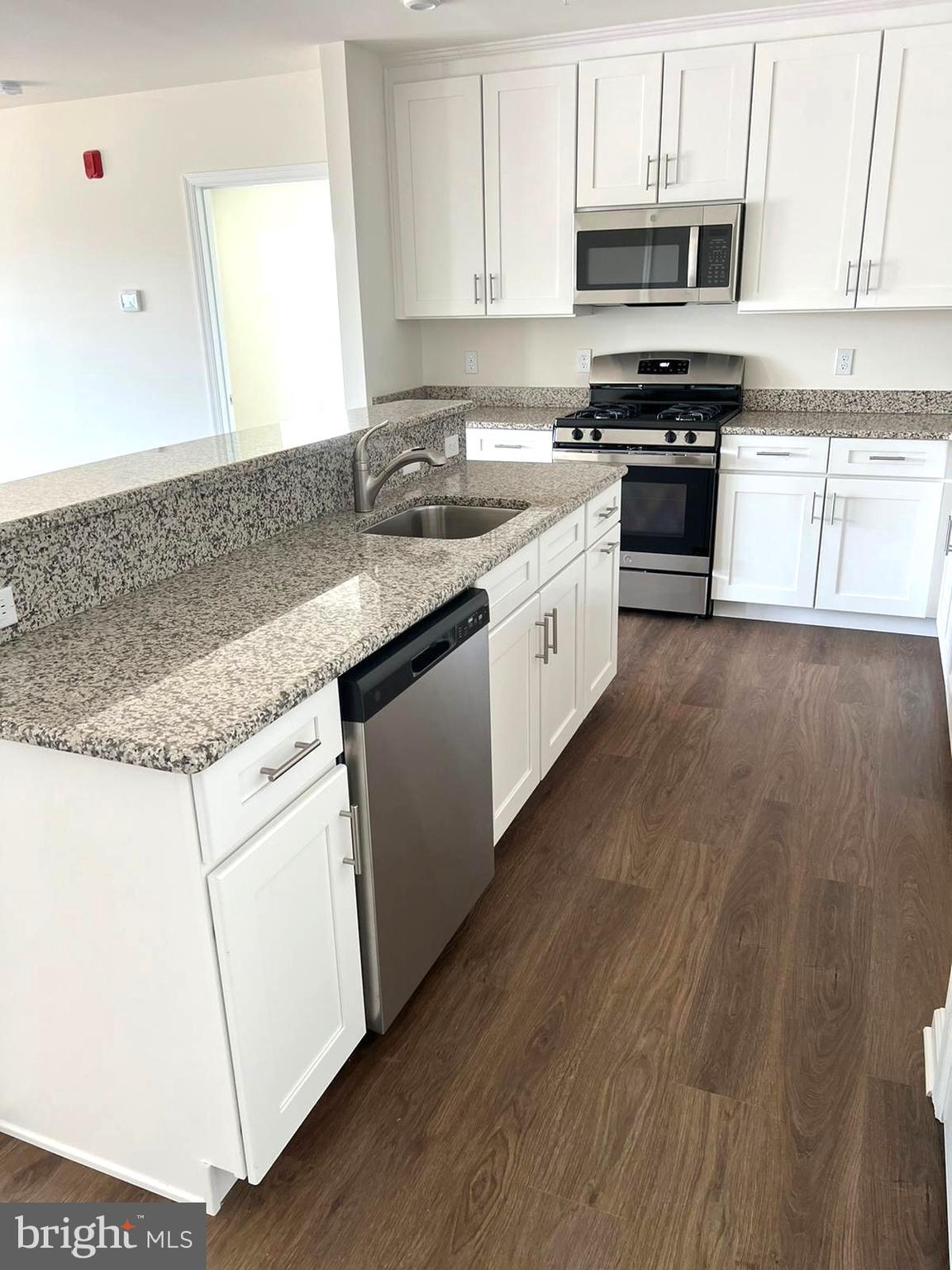 20141 Riesling Lane, Unit 309 Lewes, DE 19958 - Photo 3 of 12 a kitchen with stainless steel appliances granite countertop a stove a sink and white cabinets