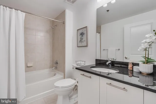 a bathroom with a granite countertop sink a toilet and shower