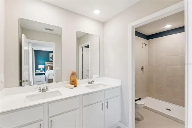a bathroom with a double vanity sink toilet and shower