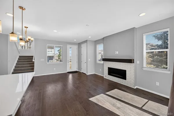 a view of an empty room with wooden floor fireplace and a window