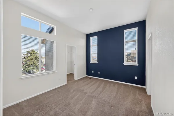 a view of an empty room with windows and closet