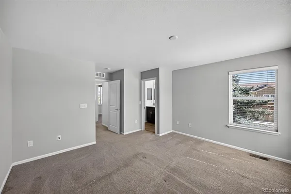 a view of an empty room with closet and windows