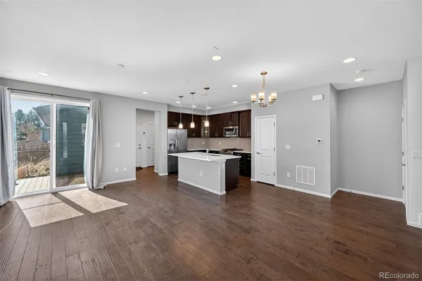 a large kitchen with a large counter top a sink stainless steel appliances and cabinets