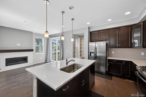 a kitchen with stainless steel appliances granite countertop a sink a stove a refrigerator and a fireplace with wooden floor