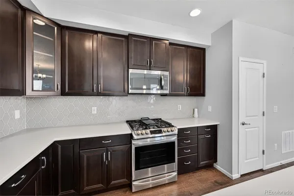 a kitchen with stainless steel appliances granite countertop white cabinets and black stove top oven with wooden floor
