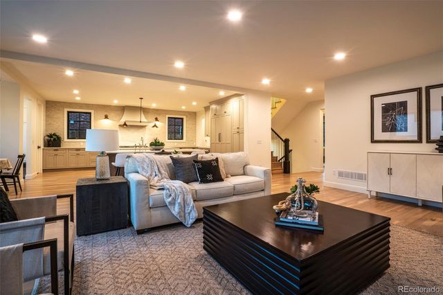 a living room with furniture kitchen view and a wooden floor
