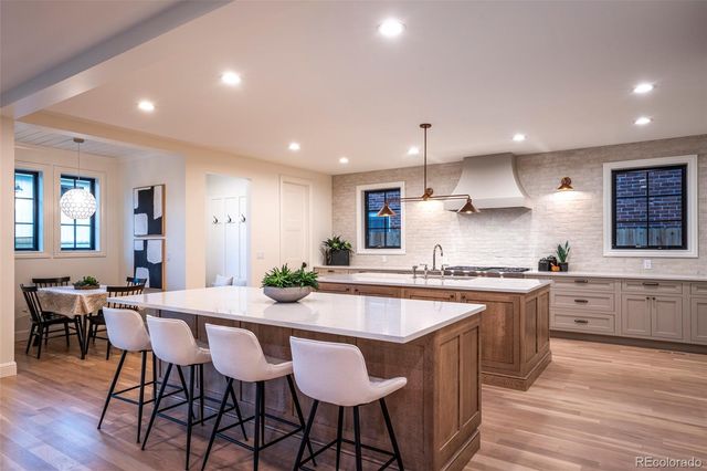 a kitchen with stainless steel appliances granite countertop a stove a sink a kitchen island with chairs and wooden floor