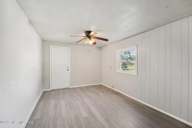 an empty room with a window and a ceiling fan