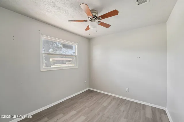 an empty room with a ceiling fan and window
