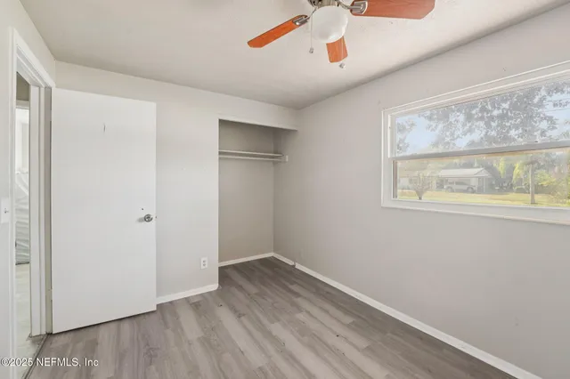 a view of empty room with wooden floor and fan