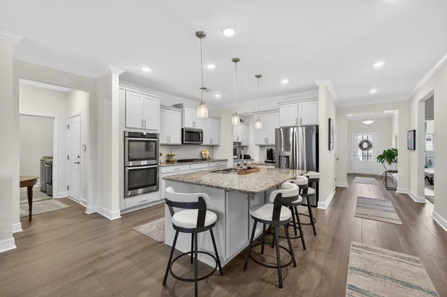 a kitchen with stainless steel appliances granite countertop a stove a sink a dining table and chairs