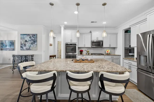 a kitchen with stainless steel appliances kitchen island granite countertop a wooden cabinets and wooden floors