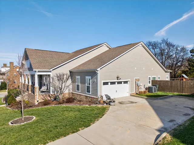 a view of a white house next to a yard with potted plants