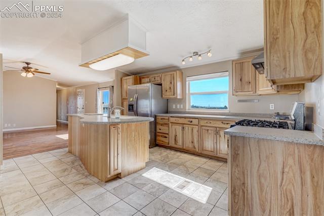 6240 Night Train Lane Yoder, CO 80864 - Photo 18 of 50 Kitchen featuring ceiling fan, stove, track lighting, light tile floors, and a kitchen island with sink