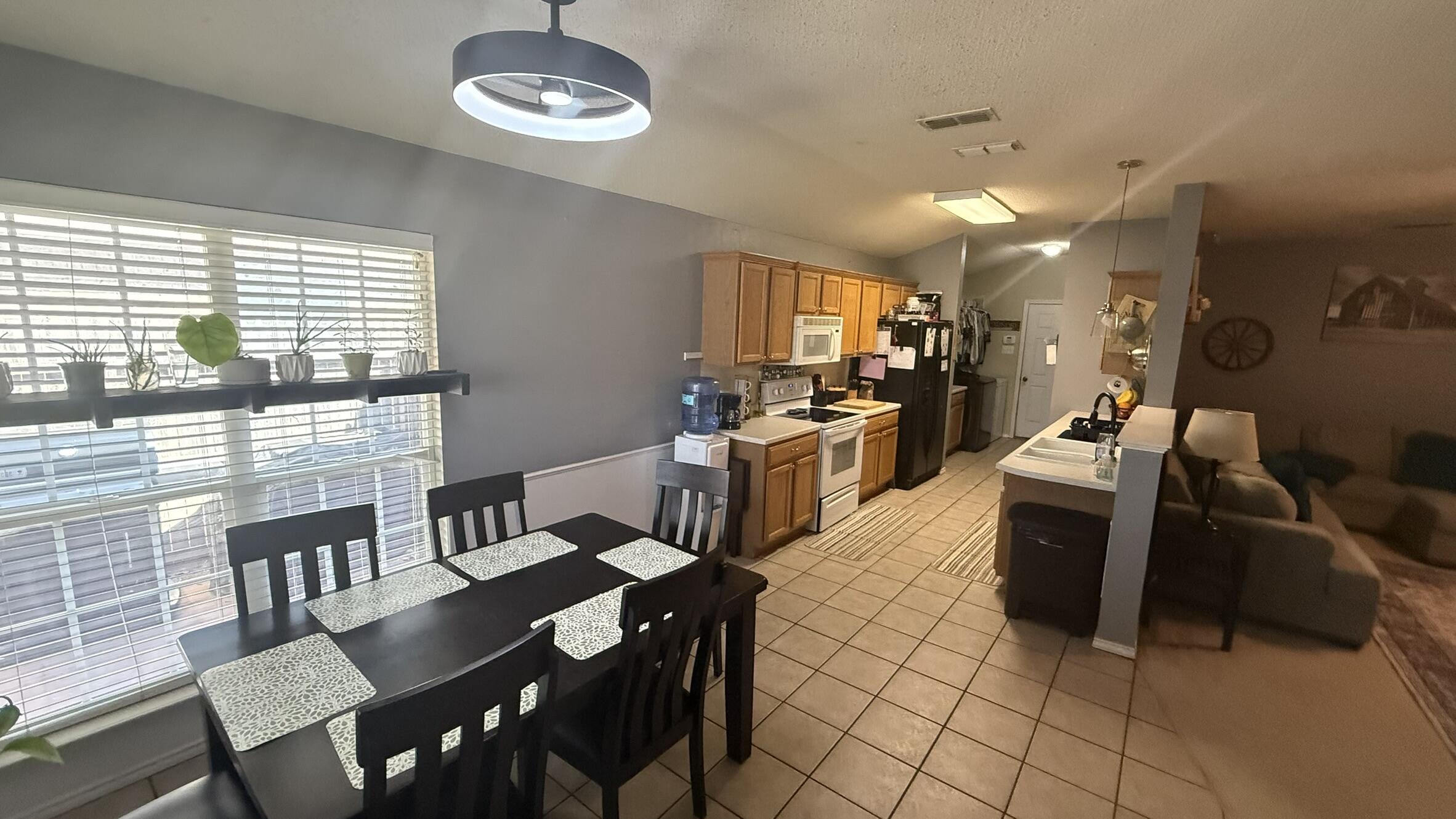 6808 84th Street Lubbock, TX 79424 - Photo 4 of 11 a kitchen with stainless steel appliances granite countertop a stove a sink a dining table and chairs with wooden floor