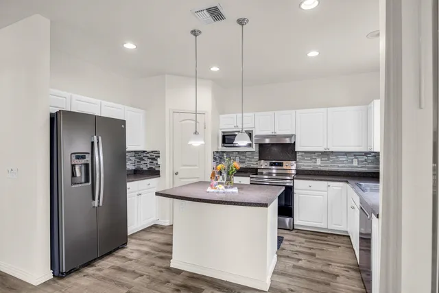 a kitchen with kitchen island stainless steel appliances a stove a sink and a refrigerator