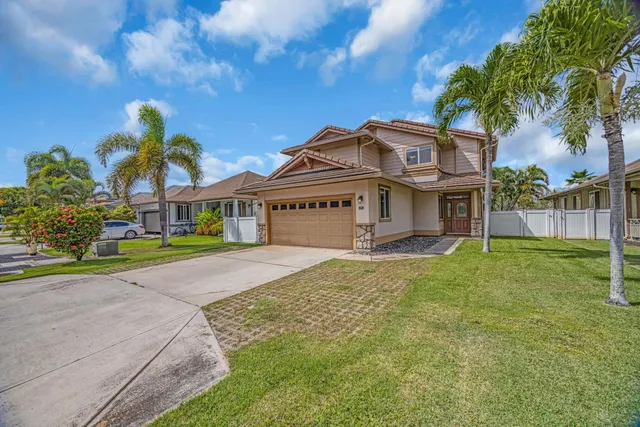 a view of a white house with a large tree and wooden fence