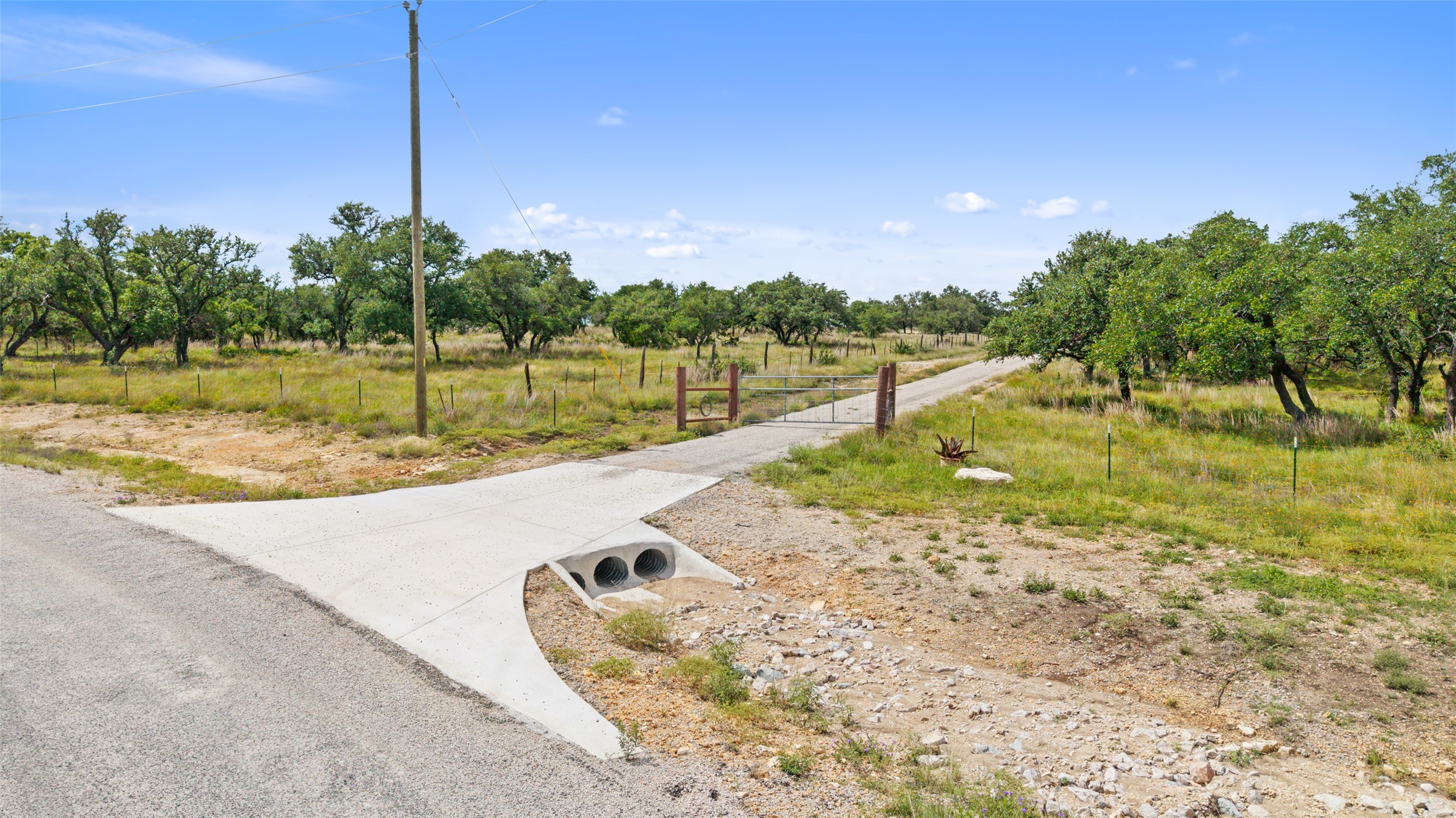 4112 Schumann Road Stonewall, TX 78671 - Photo 8 of 10 A private, gated driveway extends through a verdant landscape, inviting tranquil country living.