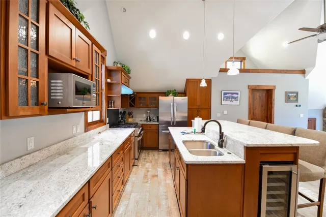 a kitchen with stainless steel appliances granite countertop a sink a stove and a wooden cabinets