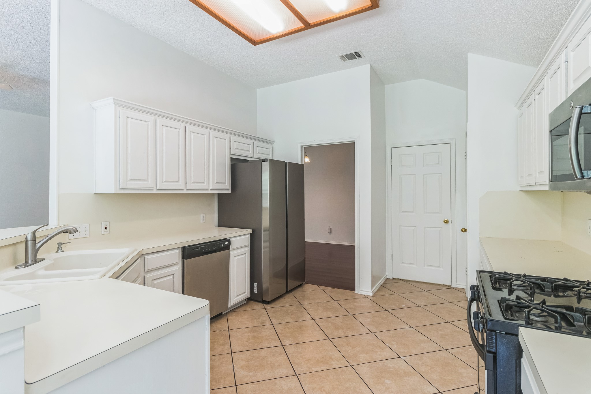 800 Mountain Ridge Drive Leander, TX 78641 - Photo 13 of 31 White cabinetry and ceramic tile flooring define this functional kitchen layout.
