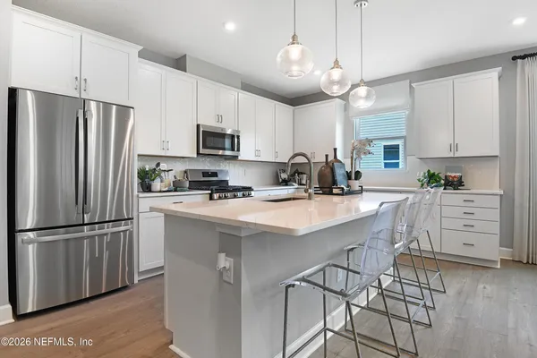 a kitchen with stainless steel appliances a refrigerator a stove a sink and white cabinets