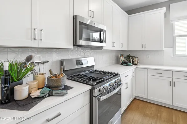 a kitchen with granite countertop a stove a sink and white cabinets