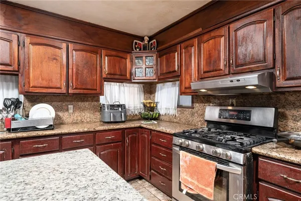 a kitchen with granite countertop wooden cabinets and a stove top oven