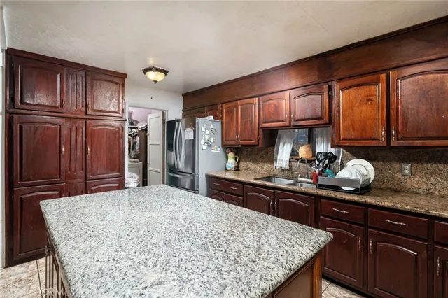 a kitchen with stainless steel appliances granite countertop a sink refrigerator and cabinets