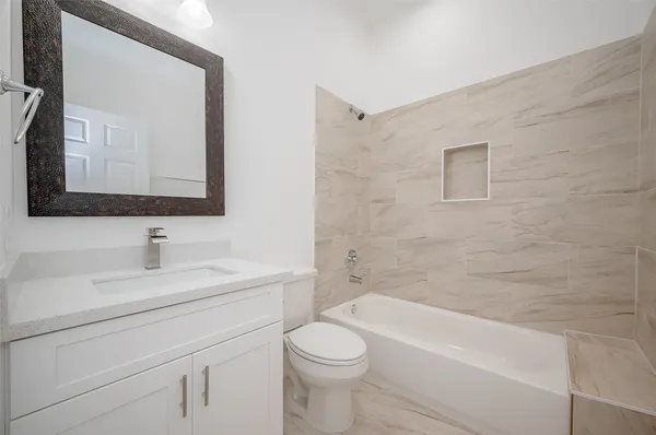 a bathroom with a toilet a sink a mirror and bathtub