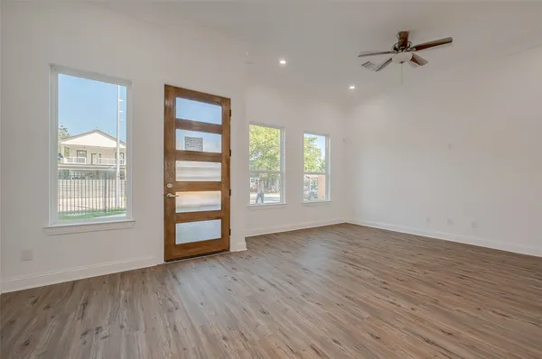an empty room with wooden floor chandelier fan and windows