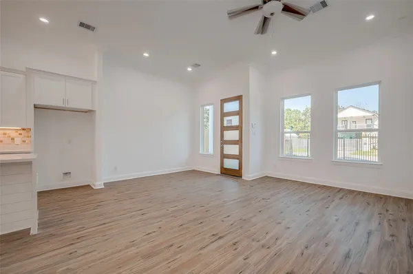 an empty room with wooden floor and windows