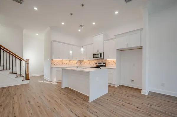 a kitchen with stainless steel appliances a refrigerator and wooden floor