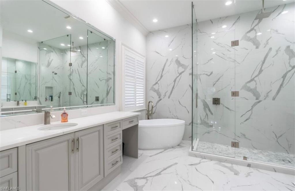 428 Rudder Road Naples, FL 34102 - Photo 10 of 47 Full bathroom with stone wall, a marble finish shower, light marble finish floors, a soaking tub, and vanity