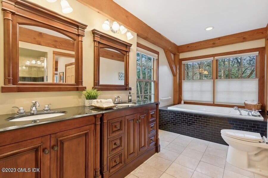 96 Cat Rock Road Cos Cob, CT 06807 - Photo 14 of 38 a spacious bathroom with a sink a mirror and a bathtub next to a window
