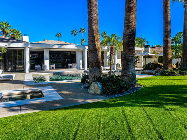 a view of a patio with couches table and chairs under an umbrella