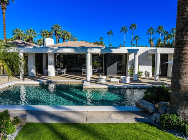 a view of a patio with couches table and chairs under an umbrella with a fire pit