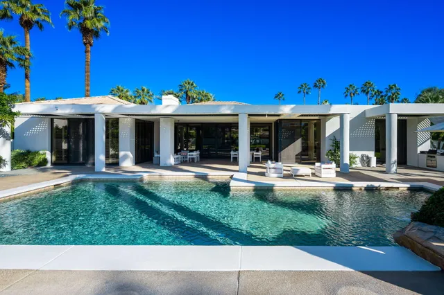 a front view of a house with a yard and potted plants