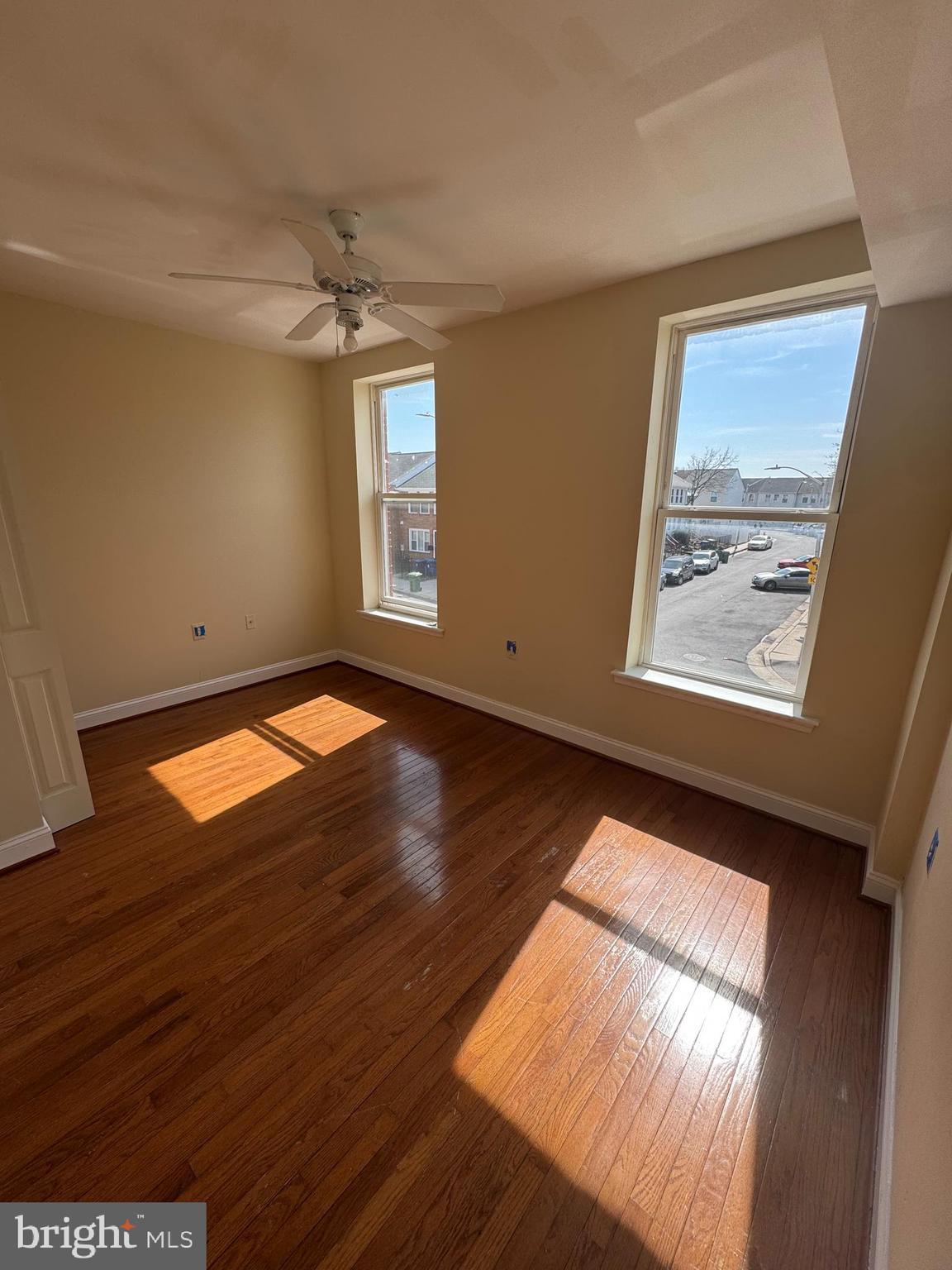 a view of an empty room with wooden floor and a window