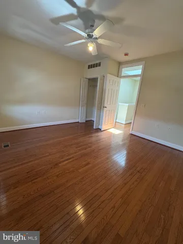an empty room with wooden floor and a ceiling fan