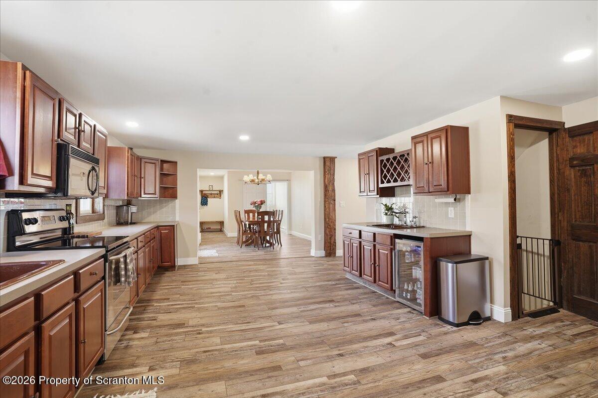 6105 State Rte 2012 Union Dale, PA 18470 - Photo 15 of 79 a large kitchen with stainless steel appliances granite countertop a refrigerator a stove top oven a sink dishwasher and wooden cabinets with wooden floor