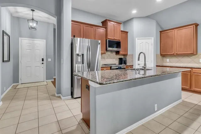 a kitchen with stainless steel appliances granite countertop a sink a stove a refrigerator and a dining table